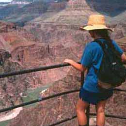 A backpacker looks over the rail at the Grand Canyon